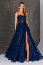 Woman wearing a navy blue evening gown with a slit on a gray background