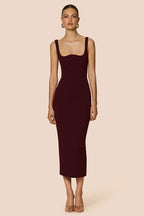 Woman wearing a burgundy dress with a backless design on a beige background