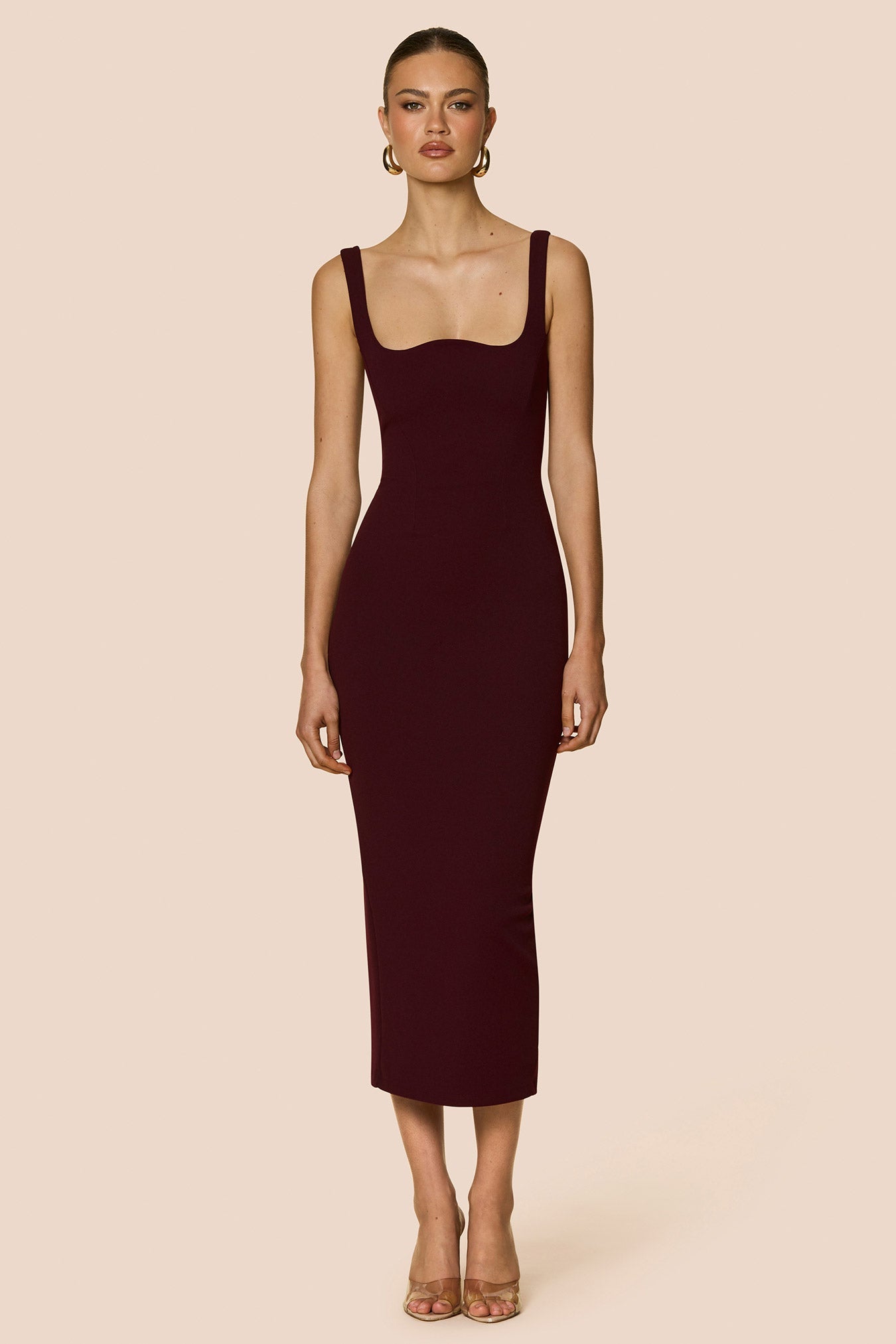 Woman wearing a burgundy dress with a backless design on a beige background