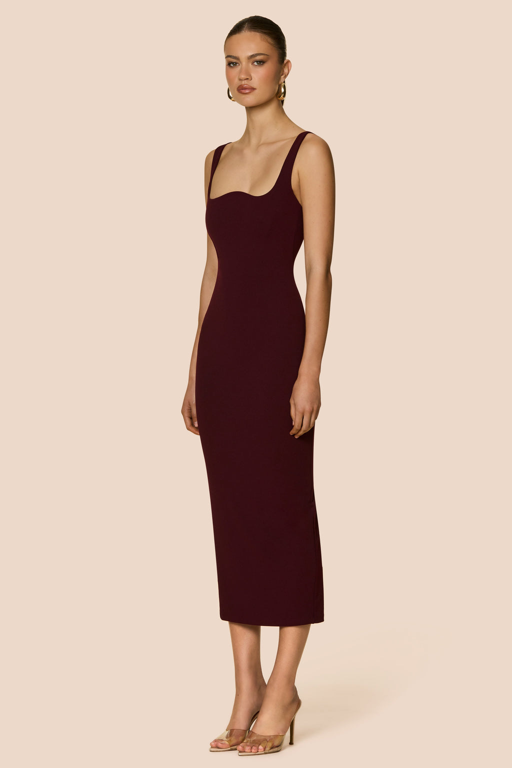 Woman wearing a burgundy dress with a backless design on a beige background
