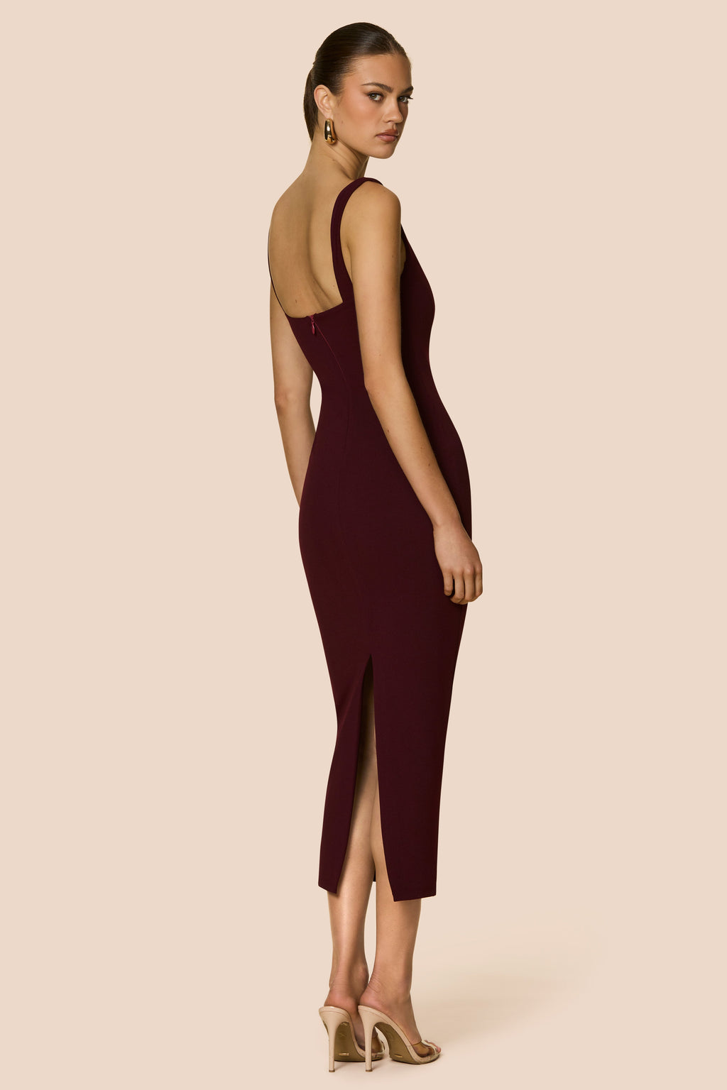 Woman wearing a burgundy dress with a backless design on a beige background