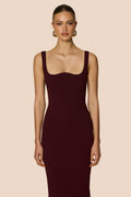 Woman wearing a dark red dress against a beige background