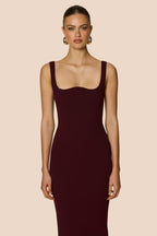 Woman wearing a dark red dress against a beige background