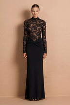 Woman wearing a black lace dress against a beige background