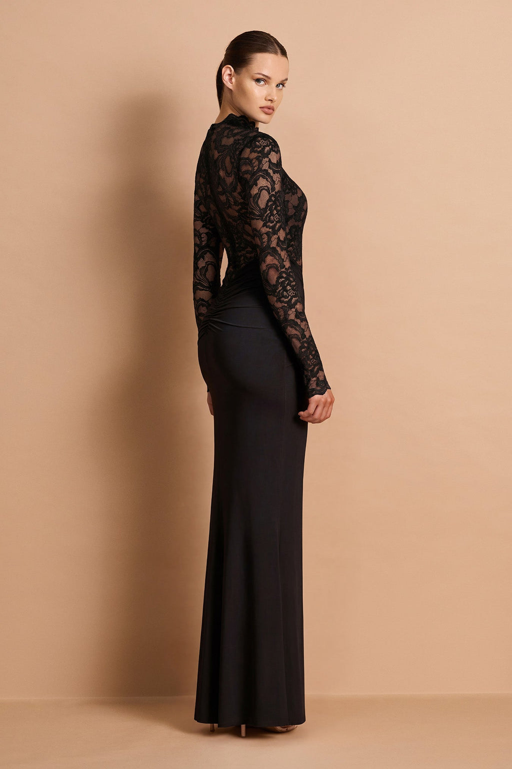Woman wearing a black lace long-sleeve dress against a beige background