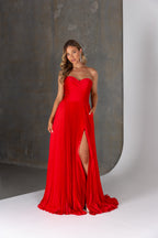 Woman wearing a red strapless gown with a high slit on a neutral background