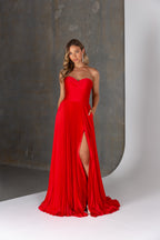 Woman wearing a red strapless gown with a high slit on a neutral background