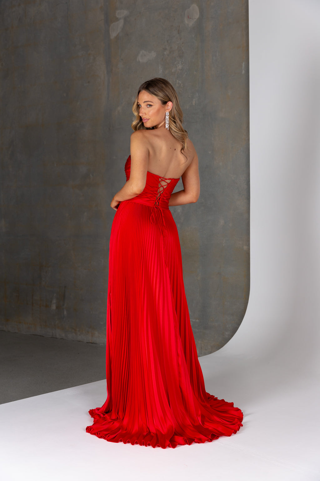 Woman wearing a red evening gown against a neutral background