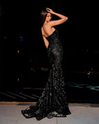 Woman in a black evening gown posing outdoors at night.