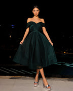 Woman wearing a dark green off-shoulder dress at night.