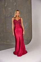 Woman wearing a red evening gown with intricate detailing against a neutral background