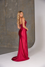 Woman in a red evening gown standing against a neutral background