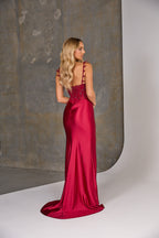 Woman wearing a red evening gown with a textured wall background