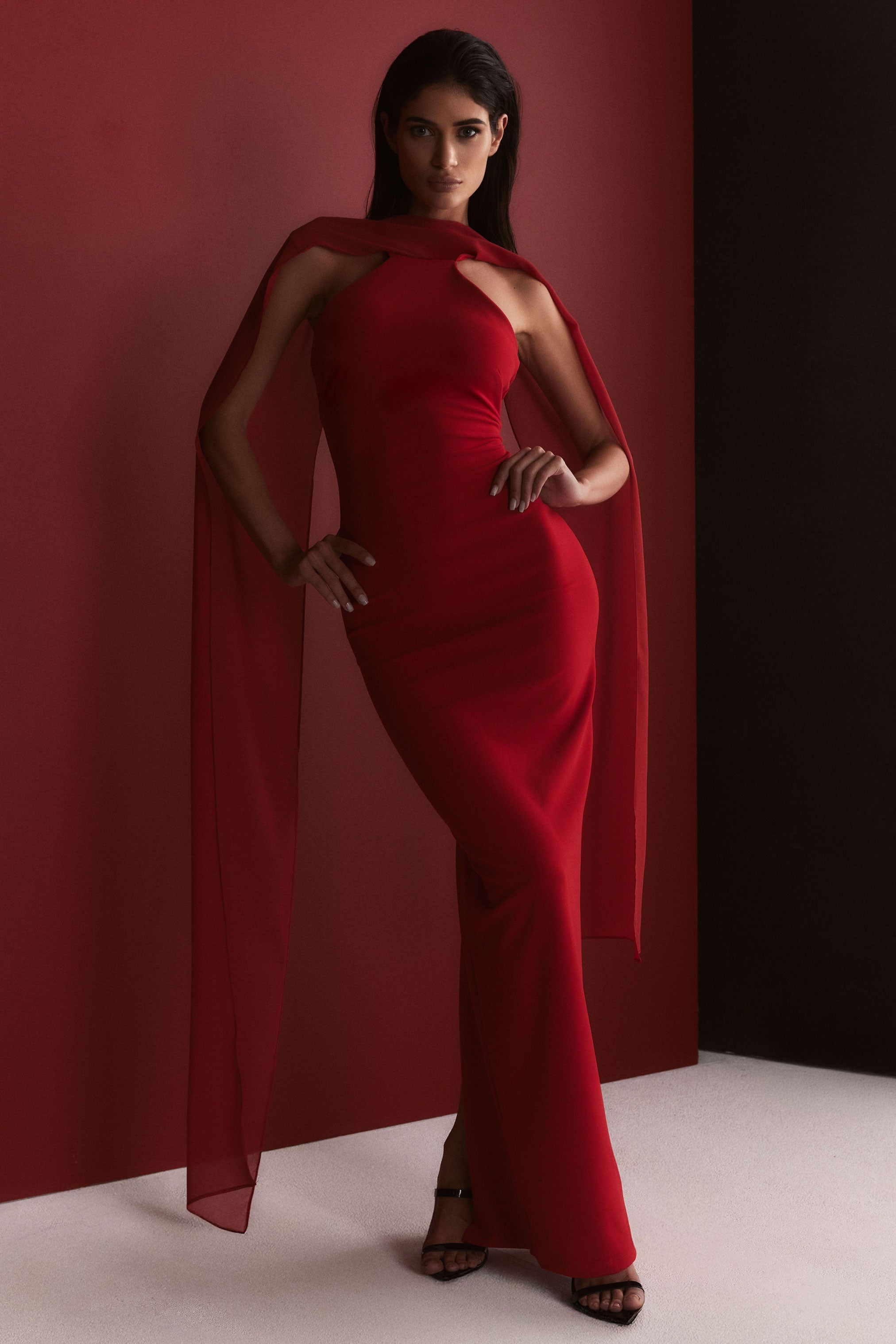 Woman wearing a red dress with a cape against a red background