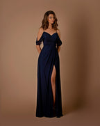 Woman wearing a navy blue evening gown with a slit on a brown background