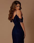 Woman wearing a navy blue evening gown with sheer sleeves on a brown background