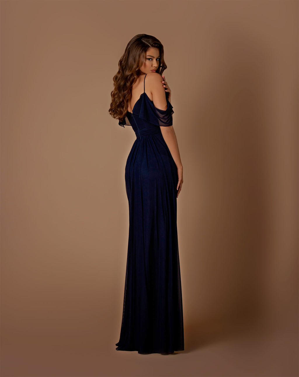 Woman wearing a navy blue evening gown against a brown background