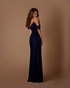 Woman wearing a navy blue evening gown against a brown background
