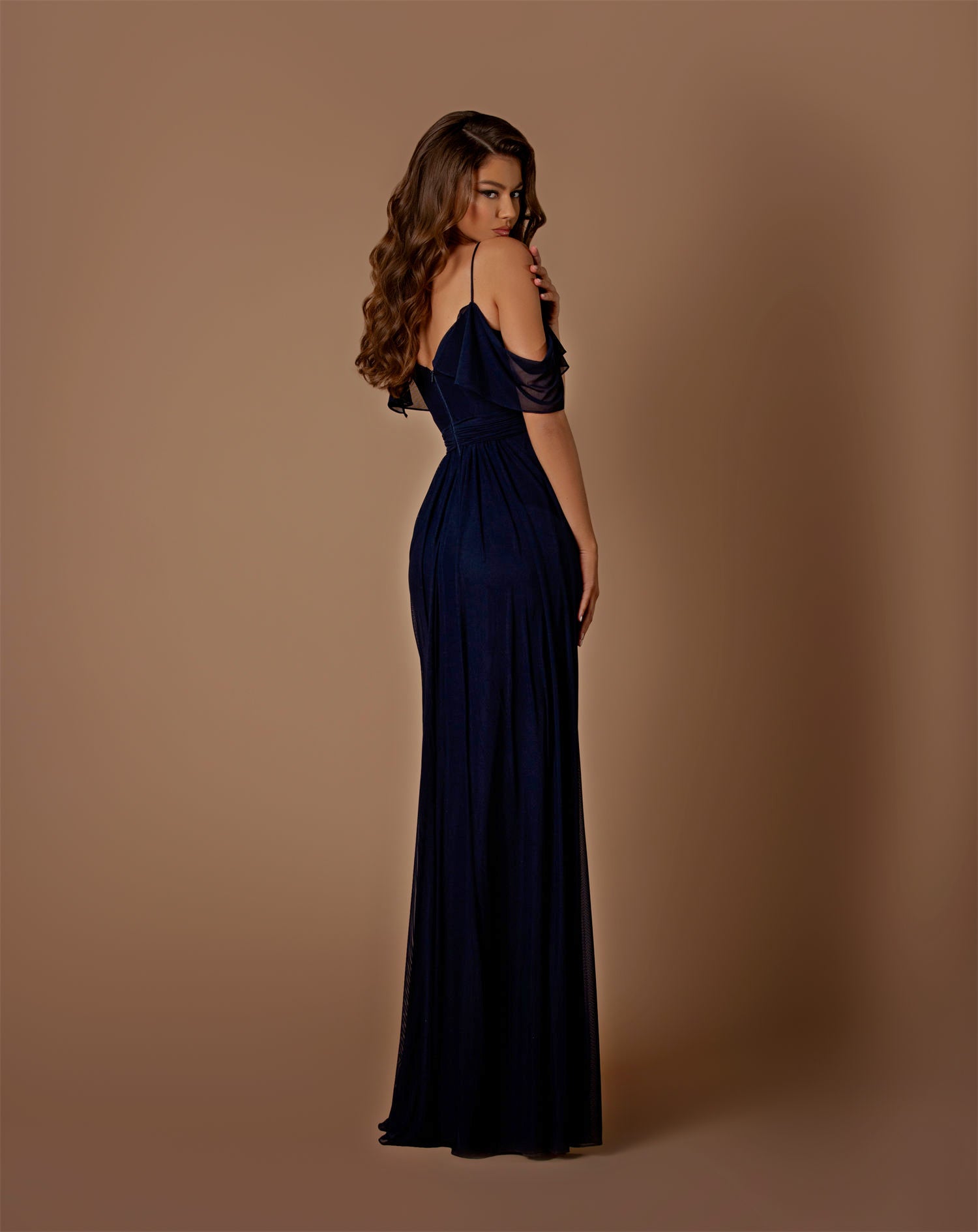Woman wearing a navy blue evening gown against a brown background