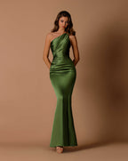 Woman wearing a green one-shoulder dress against a brown background