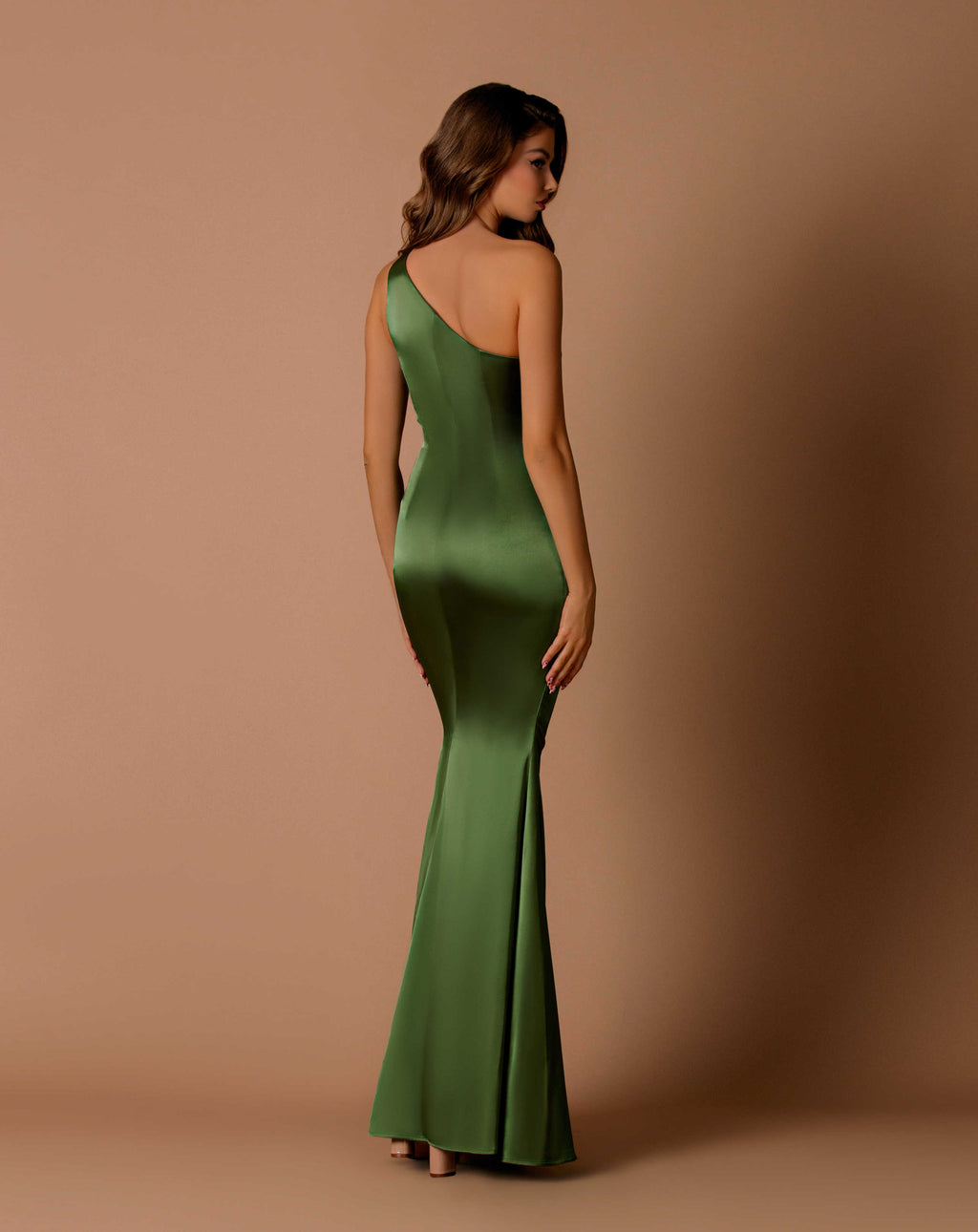 Woman wearing a green one-shoulder dress against a brown background