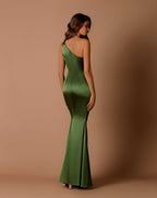 Woman wearing a green one-shoulder dress against a brown background