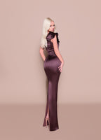 Woman wearing a long, dark purple dress with a high slit on a beige background