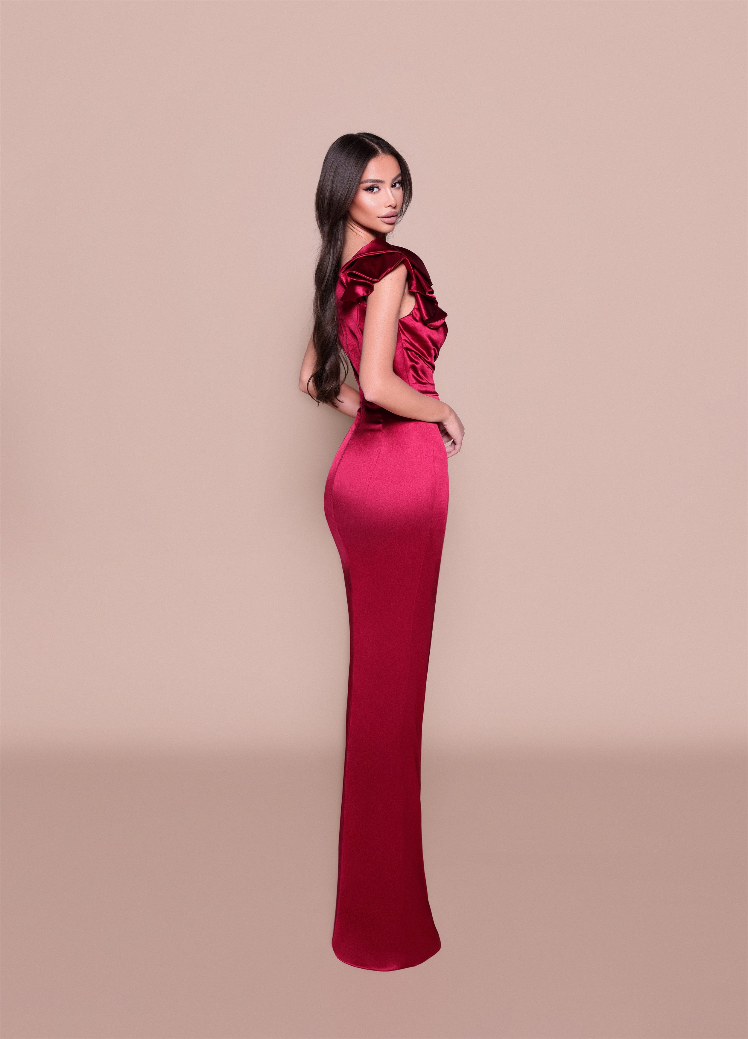 Woman wearing a red evening gown with a beige background