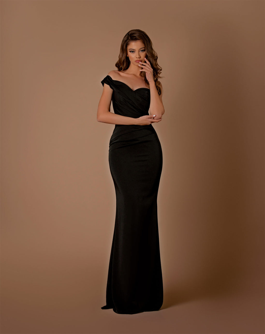 Woman wearing a black off-shoulder gown against a brown background