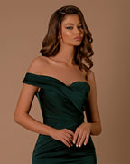 Woman wearing a green off-shoulder dress against a brown background