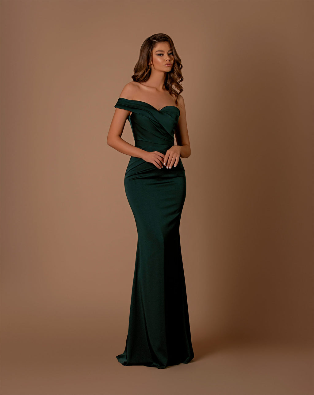 Woman wearing a green off-shoulder gown against a brown background