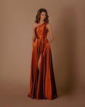 Woman wearing a rust-colored one-shoulder gown with a slit on a brown background