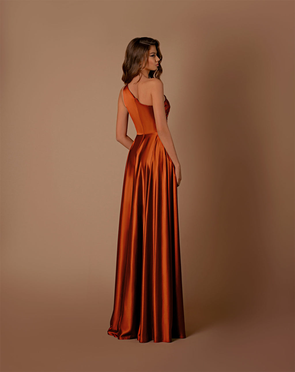 Woman wearing an orange satin gown against a brown background