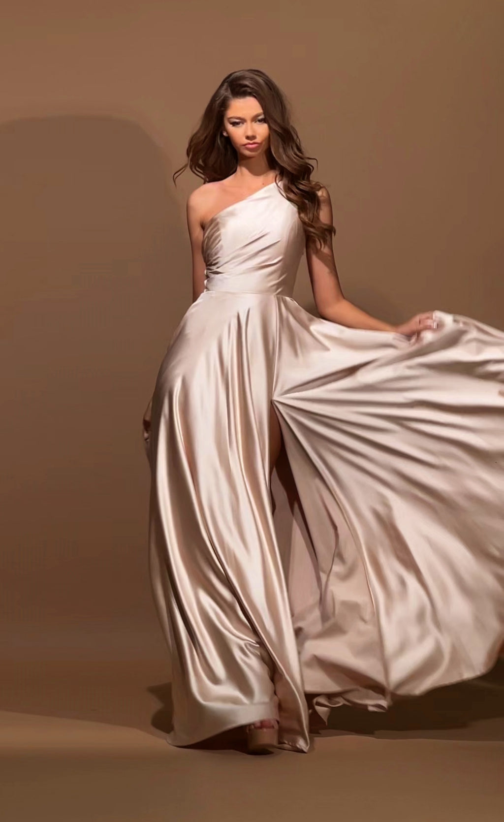 Woman in a flowing white dress against a brown background