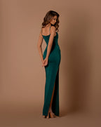 Woman wearing a green evening gown with a high slit on a brown background