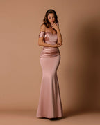 Woman wearing a pink satin gown against a beige background