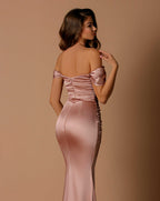 Woman wearing a pink satin off-shoulder gown against a beige background