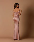 Woman wearing a pink satin evening gown against a beige background