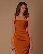 Woman wearing an orange dress against a brown background