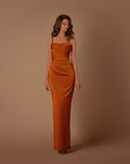 Woman wearing a rust-colored strapless gown against a brown background