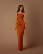 Woman wearing a rust-colored strapless gown against a brown background