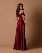 Woman wearing a burgundy off-shoulder gown against a beige background