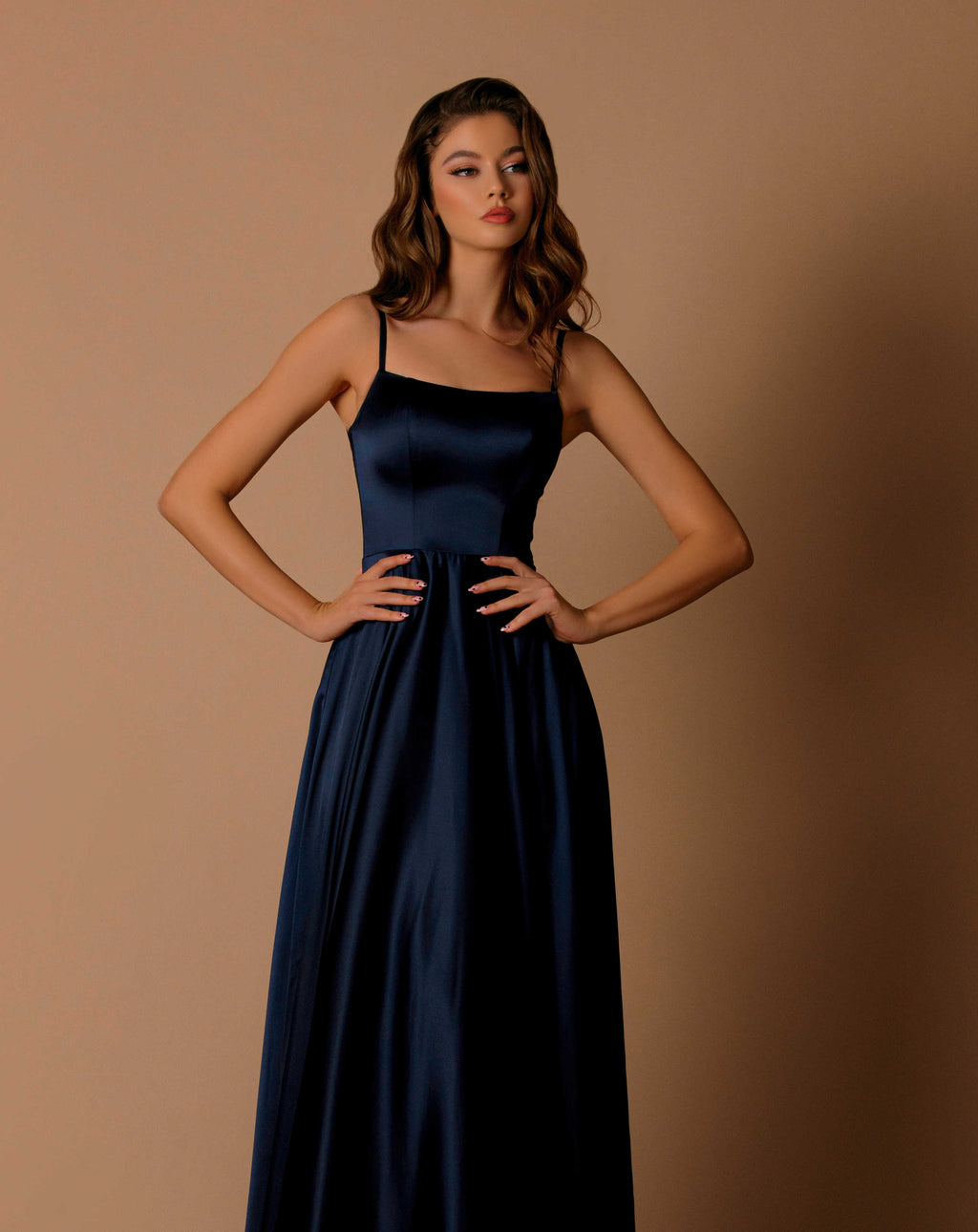 Woman wearing a navy blue dress against a brown background