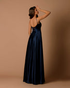 Woman wearing a navy blue evening gown against a beige background