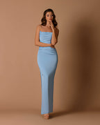 Woman wearing a light blue strapless gown against a brown background