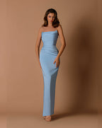 Woman wearing a strapless blue gown against a brown background