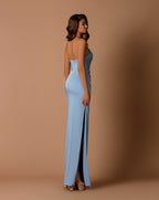 Woman wearing a light blue strapless gown with a high slit on a brown background