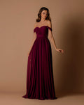 Woman wearing a burgundy off-shoulder gown against a brown background