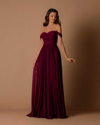 Woman wearing a burgundy off-shoulder gown against a brown background