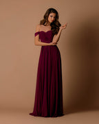 Woman wearing a burgundy off-shoulder gown against a brown background